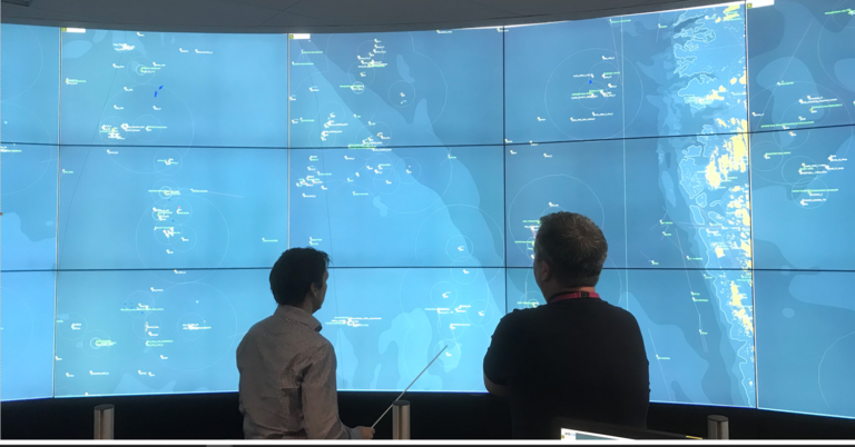 two people in front of a megawall of screens monitoring vessel activity in real time